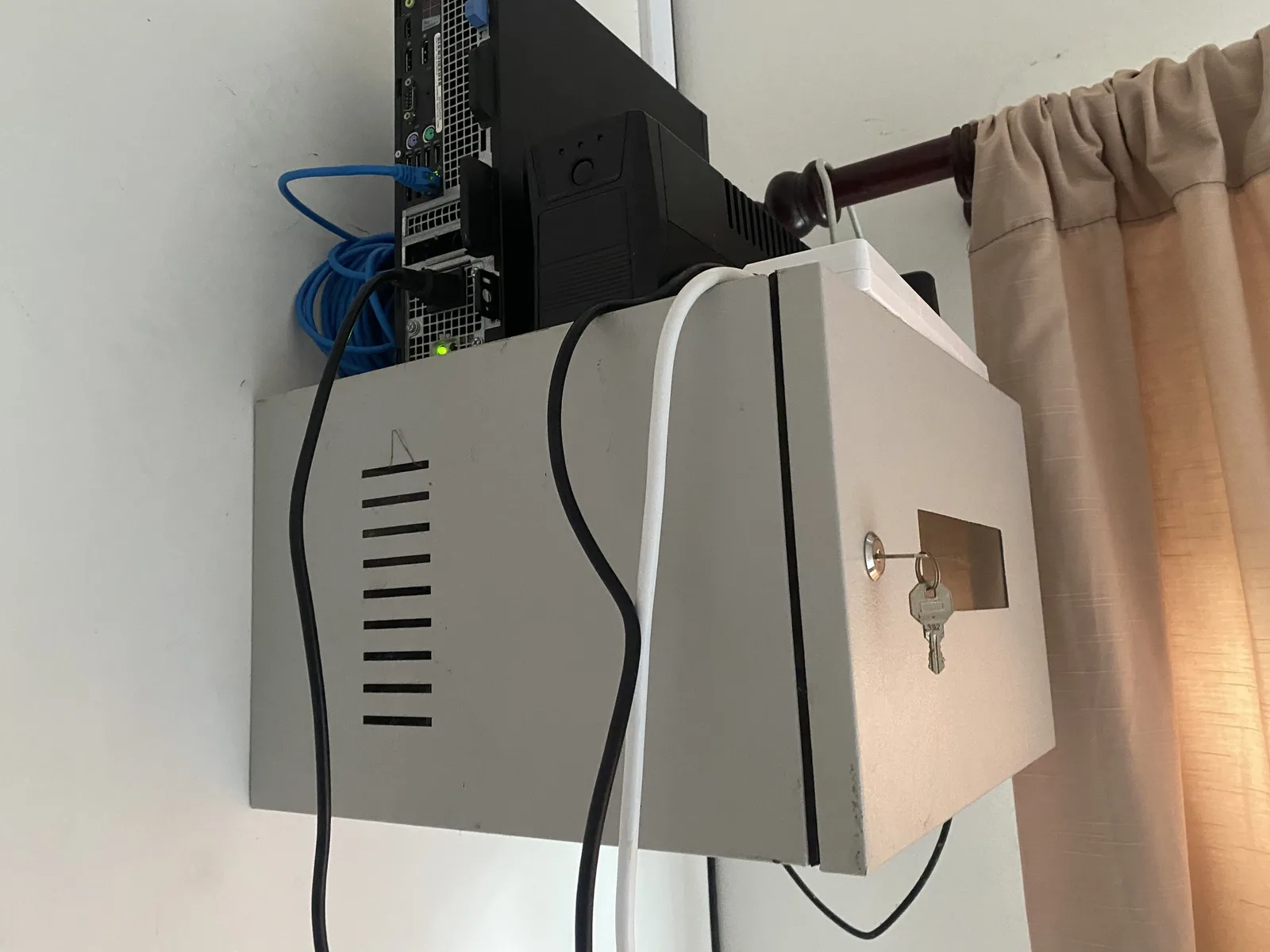Low-angle view of the home-lab server and UPS above a locked metal cabinet
